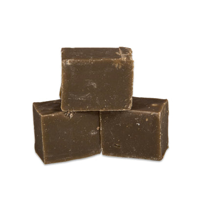 Three pieces of dark chocolate fudge stacked on a white background