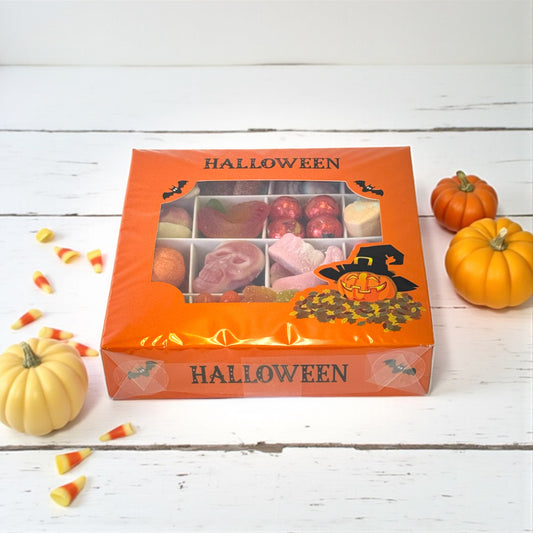Lollypop Lane halloween gift box filled with spooky shaped sweets. The background has pumpkins a teeth laying on the table.
