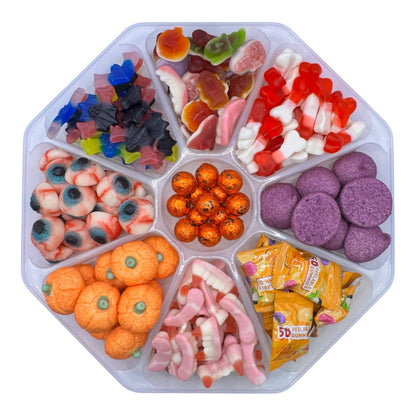 A clear plastic octagonal candy tray divided into multiple compartments filled with assorted Halloween-themed gummy candies, including orange pumpkins, purple circles, eyeballs, gummy worms, and wrapped 50-count candy pieces, on a white background.