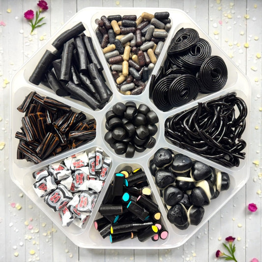 Lollypop Lane sweet platter filled with an assortment of black liquorice sweets on a white wooden table with some succulents.