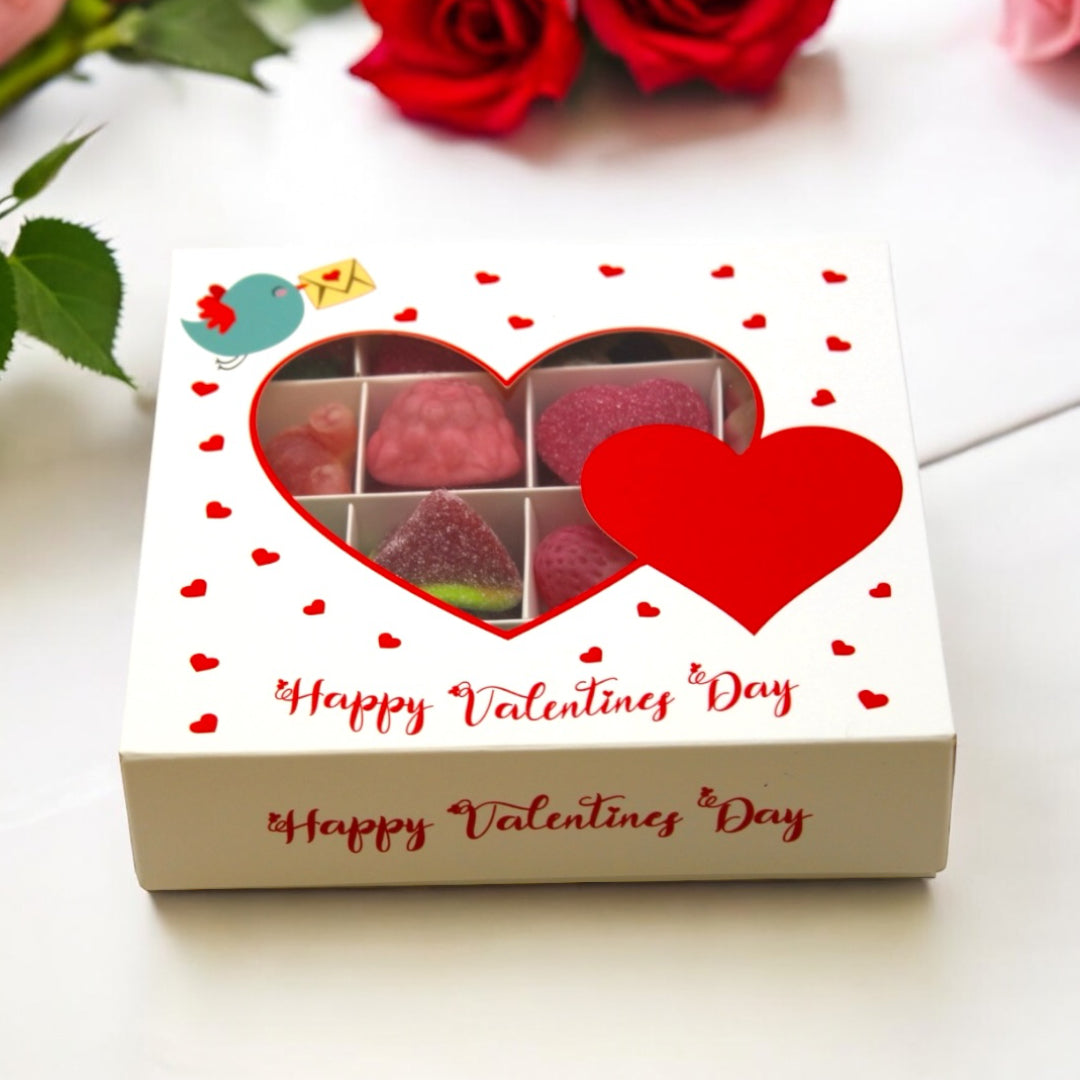 Lollypop Lane Valentine Jelly Filled Sweets Gift Box (16 Sweets) on a table surrounded by roses.