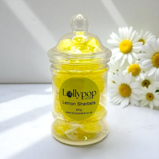 Jar of lemon sherbets with a 'Lollypop Lane' label, surrounded by daisies on a white background.