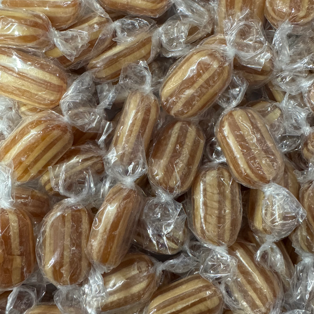 A close-up pile of individually wrapped mint humbugs with a striped pattern of light and dark brown sugar.