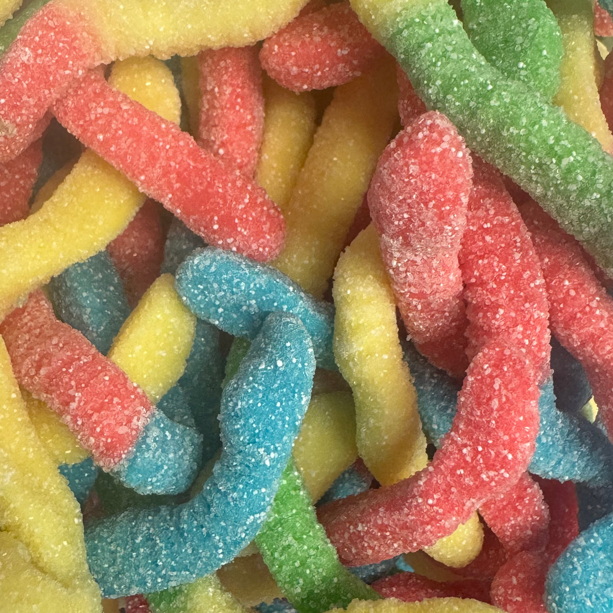 A close-up pile of sour candy worms coated in sugar, showing multiple colors including red, yellow, blue, green, and orange.