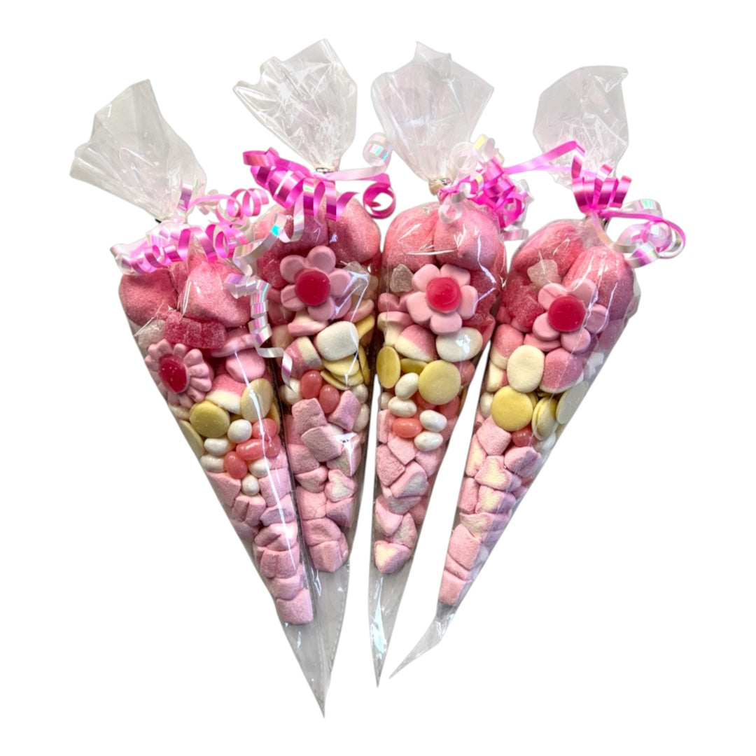 Four individually wrapped cone-shaped candy gift bags filled with pink and pastel lollipops, flower-shaped candies, and round sweets, tied with pink ribbons on a white background.