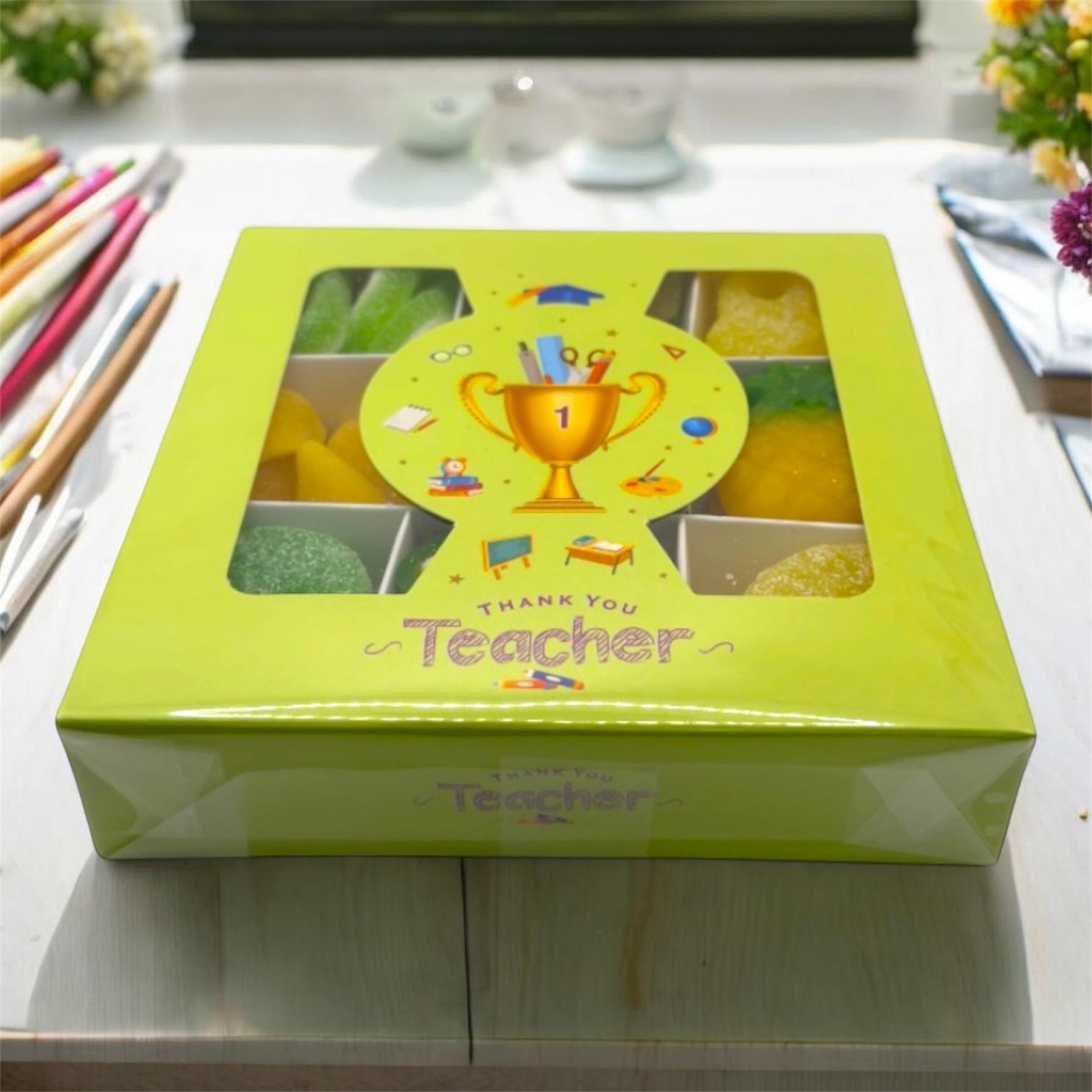 Green gift box with 'Thank You Teacher' text and graphics on a light surface.