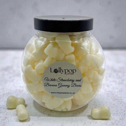 Lollypop Lane Mini Sweet Jar filled with White Strawberry and Banana Gummy Bears. The background features a marble surface.