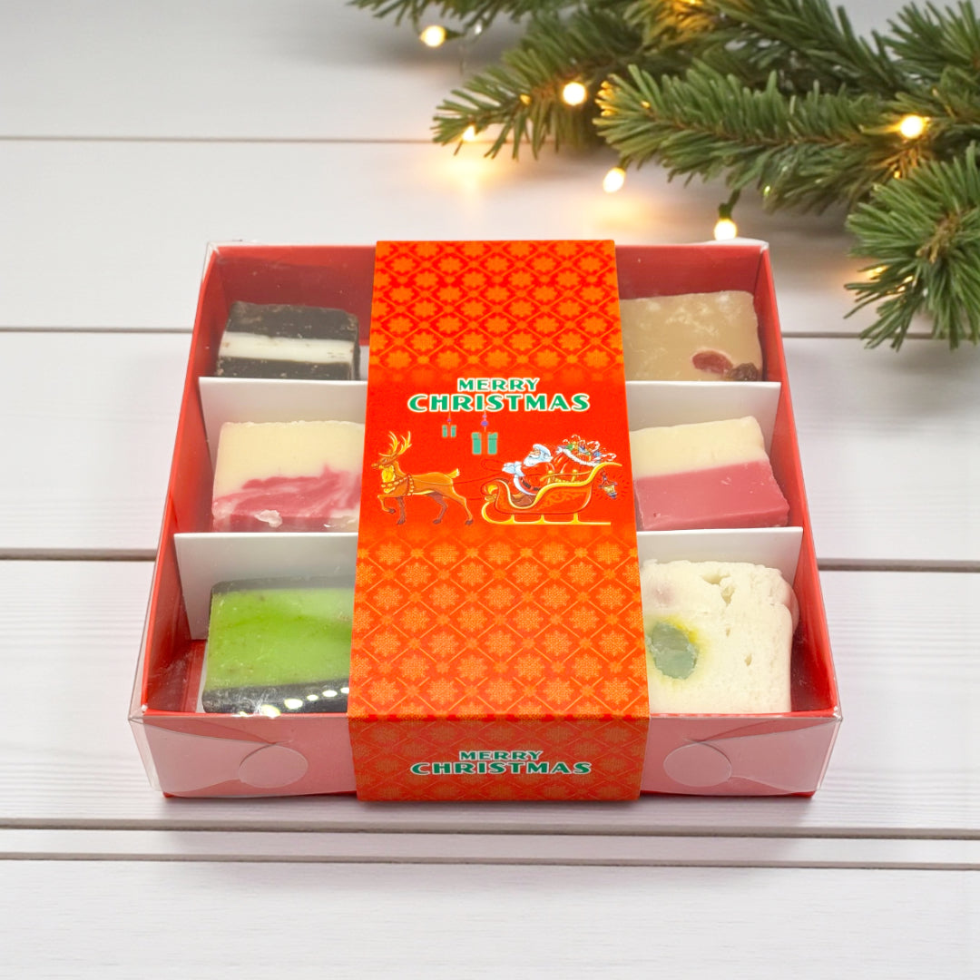 Lollypop Lane Christmas Gift Box Filled with Fudge. The background features a wooden table and xmas foliage.
