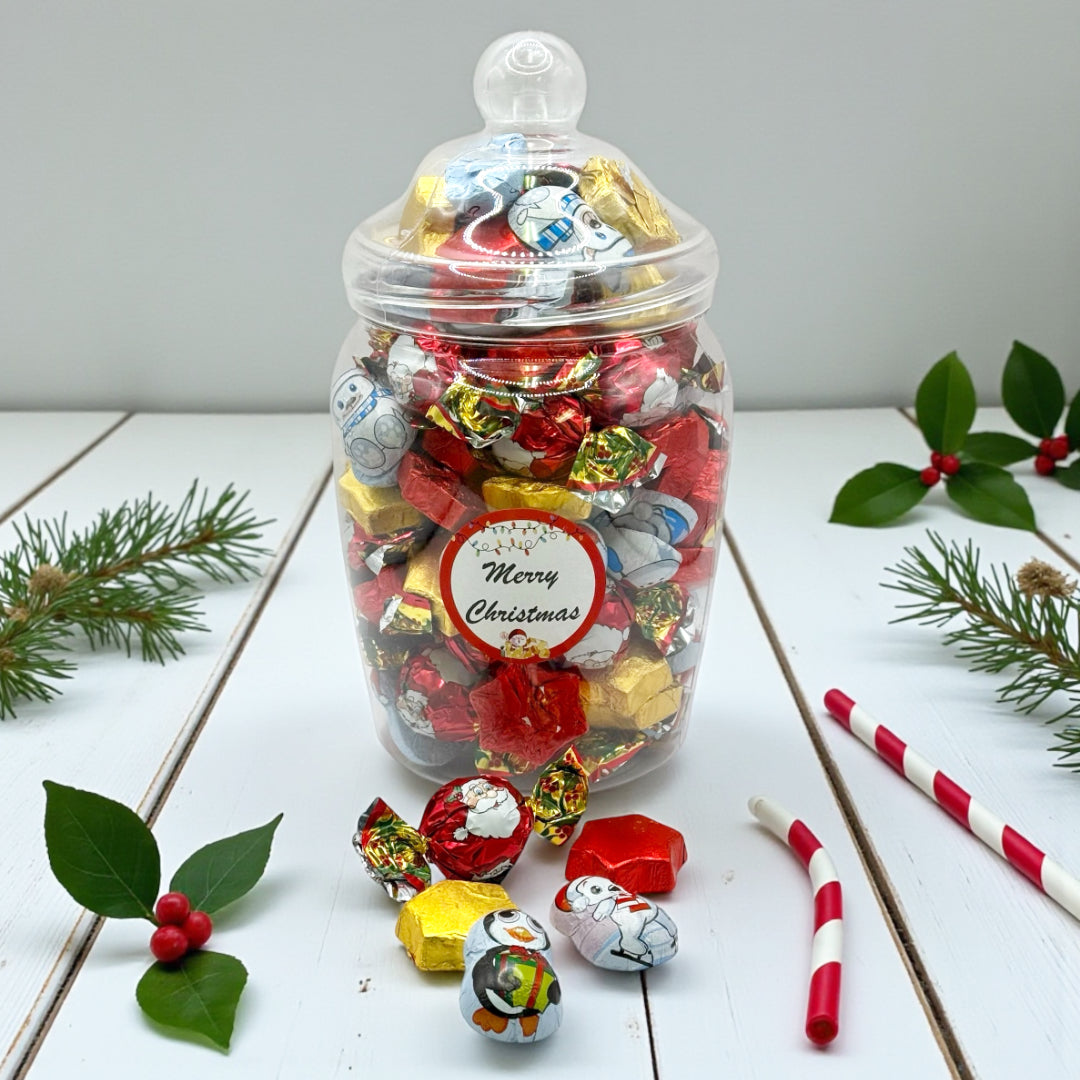 Milk Chocolate Christmas Assortment Christmas Jar 1kg. The background features a wooden table and Christmas foliage